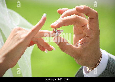 Close-up of groom’s hand putting wedding ring on bride’s finger Stock Photo
