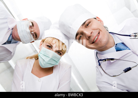 Below view of happy doctors with nurse between them looking at camera Stock Photo