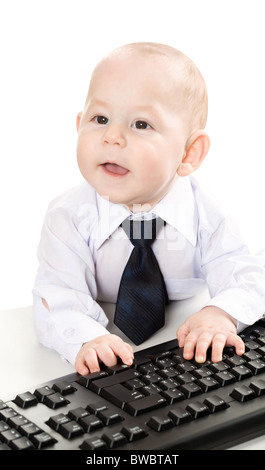 Portrait of cheerful baby boy typing on keyboard and looking aside Stock Photo