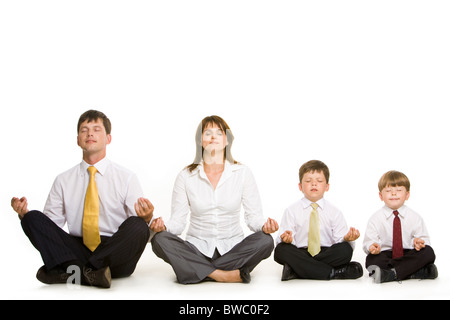 Photo of peaceful family sitting in pose of lotus in a row and meditating over white background Stock Photo