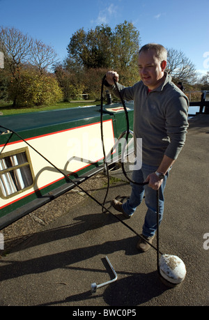 man holding canal boat roped on to bollard waiting for lock Stock Photo