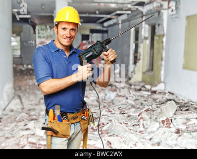 confident handyman with big drill on duty at construction site Stock Photo
