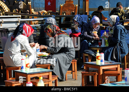 ISTANBUL, TURKEY. Young Turkish women eating balik ekmek (mackerel sandwiches) beside the Golden Horn in Eminonu district. 2010. Stock Photo