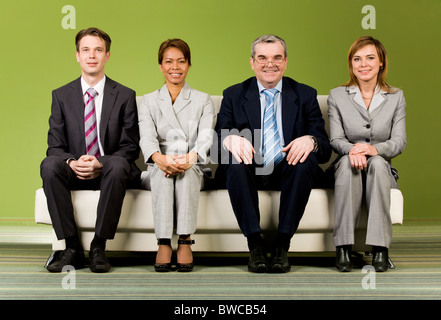 Portrait of several successful associates sitting on sofa and looking at camera Stock Photo