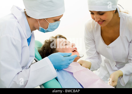 Image of dental examining being given to little boy by dentist and his assistant Stock Photo