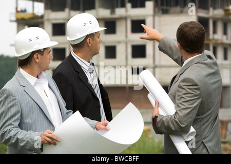 Image of three workers looking construction during discussion of architectural project Stock Photo