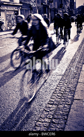 Students cycling to lectures in Cambridge in strong early winter sun