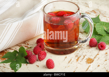 Raspberry tea in a glass cup and scattered berries Stock Photo
