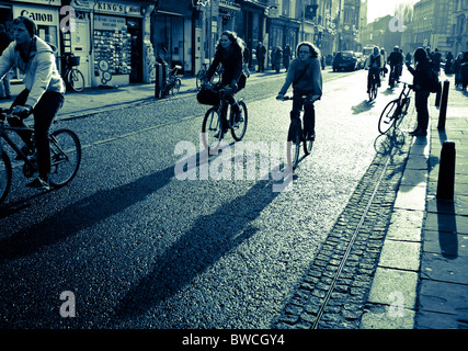 Students cycling to lectures in Cambridge in strong early winter sun