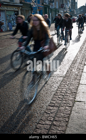 Students cycling to lectures in Cambridge in strong early winter sun