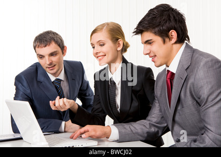 Portrait of executive employees looking at laptop monitor and discussing new project during meeting Stock Photo