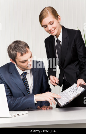 Photo of confident boss looking at documents being shown by his secretary Stock Photo