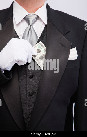 USA, Illinois, Metamora, Man wearing tuxedo holding hundred dollar banknote, mid section Stock Photo