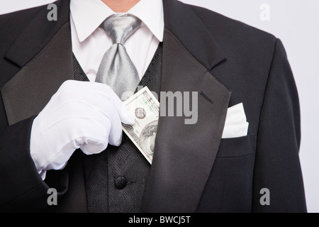 USA, Illinois, Metamora, Man wearing tuxedo holding hundred dollar banknote, mid section Stock Photo