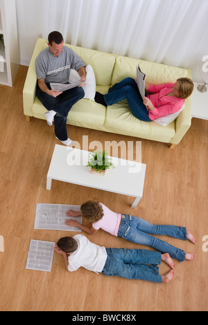 USA, Illinois, Metamora, Family reading newspapers in living room Stock Photo