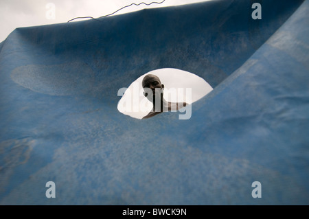 An earthquake survivor seen trhough tent made of sheet at a temporary makeshift dwelling compound in Port au Prince, Haiti Stock Photo