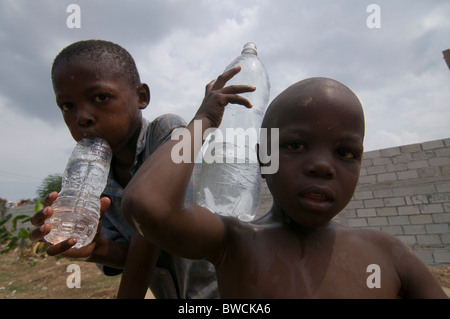 Young children with plastic bottles filled of water soon after water supply in Port au Prince, Haiti earthquake Stock Photo
