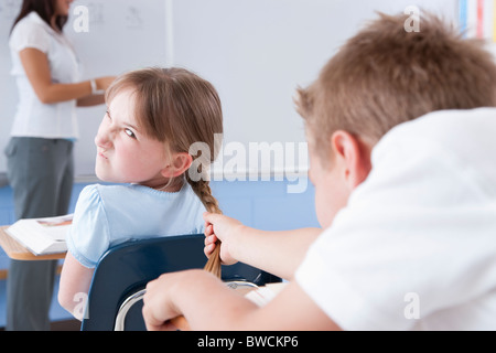 USA, Illinois, Metamora, Teacher and students (8-9) in classroom, boy bullying girl Stock Photo