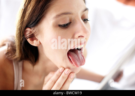 Girl looking at tongue in mirror Stock Photo