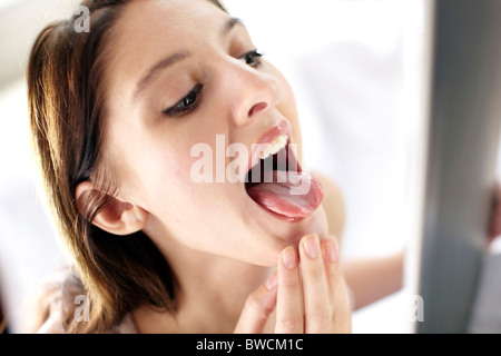 Girl looking at tongue in mirror Stock Photo