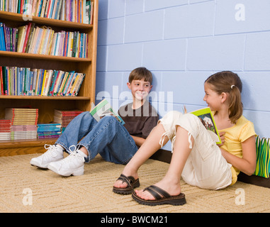 USA, Illinois, Metamora, School children (8-9) reading on floor in school Stock Photo