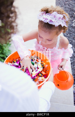 USA, Illinois, Metamora, Young woman giving candies to girl (6-7) in costume during Halloween Stock Photo