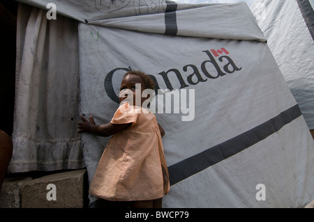 A young girl stands next to a tent donated by Canada at a makeshift camp for survivors of a 7.0 magnitude earthquake which struck Haiti on 12 January 2010 in Port-au-Prince Stock Photo