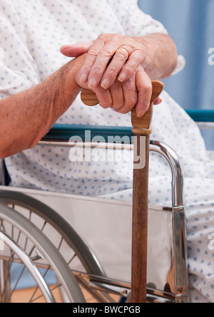 USA, Illinois, Metamora, Senior man sitting on wheelchair and holding cane, mid section Stock Photo