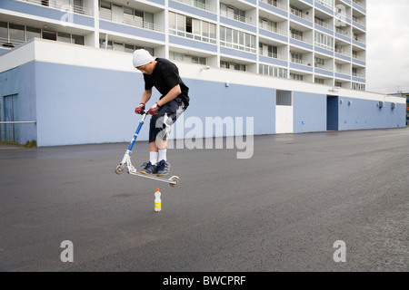 Boy jumping on a scooter outside apartment blocks. Hafnarfjordur, Greater Reykjavik Area, Iceland Stock Photo