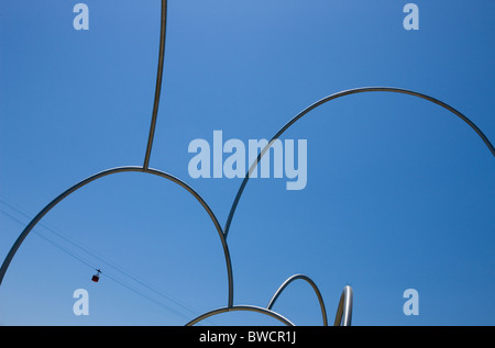 Cable car passing over Onades Waves Sculpture by Andreu Alfaro in Barcelona Stock Photo