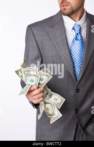 USA, Illinois, Metamora, Studio shot of man in full suit holding one dollar banknotes, mid section Stock Photo