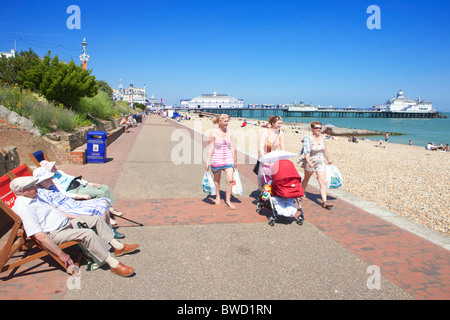 Old people on deck chairs watching young people walk along promenade; Eastbourne; East Sussex; England, Great Britain Stock Photo