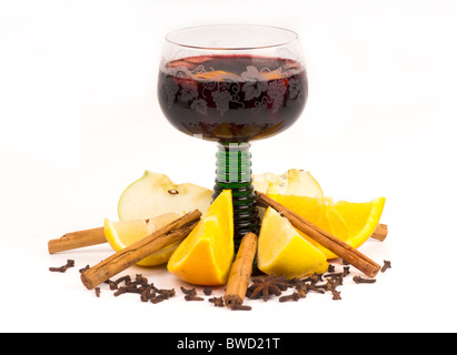 Mulled wine in a decorated German green stemmed glass surrounded by the ingredients: orange, lemon, cinnamon and cloves. Stock Photo