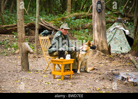 German army soldier with German Sheppard guard dog world war two acting  show sitting resting wood forest Stock Photo