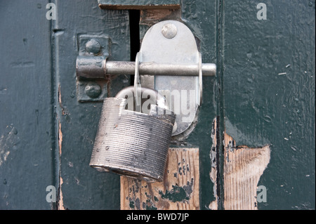 Modern steel padlock securing a bolt on a blue/grey painted wooden door Stock Photo