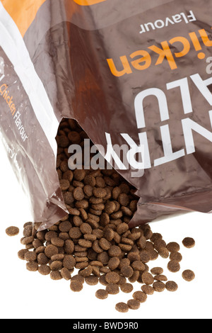 Brown complete dog biscuit food spilling from a 15 kg plastic sack Stock Photo