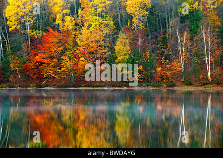 Morning fog rises from Moccasin Lake with autumn reflection in Michigan's Upper Peninsula. Stock Photo