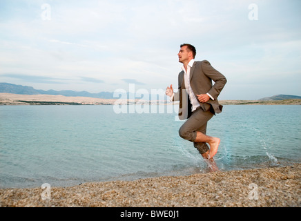 Businessman running on the beach Stock Photo