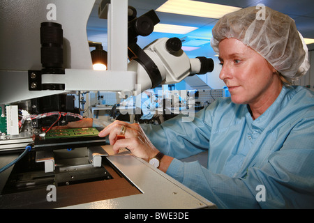 female technician using a microscope on a circuit board Stock Photo