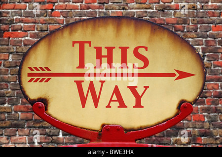 A rusty old retro arrow sign with the text This Way Stock Photo