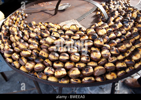 Roasted chestnuts in street Rome Italy Europe cooked on grill spot Roma Italia autumn cold Castanea sativa  detail close up Nove Stock Photo