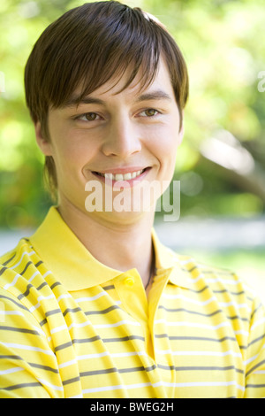 Portrait of cheerful guy wearing yellow T-shirt smiling in natural environment Stock Photo
