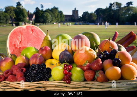 Basket of delicious fresh healthy British summer fruits in basket beside Benenden Village Green with cricket match Kent UK Stock Photo