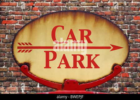 A rusty old retro arrow sign with the text Car Park