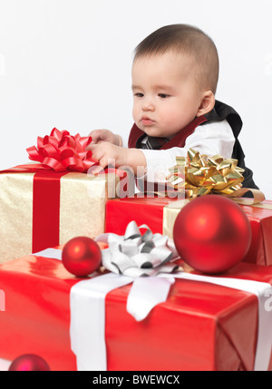 Six month old baby boy opening Christmas presents. Isolated on white background.