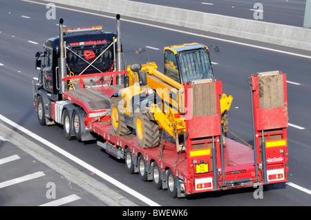 HGV lorry truck & low loader transport for JCB Bamford business diesel hydraulic construction equipment machine driving on motorway England UK Stock Photo