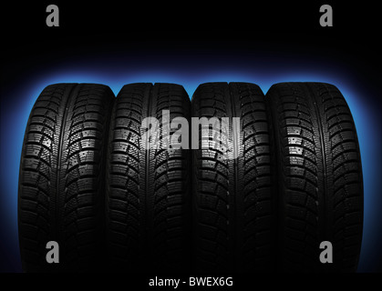 Set of four winter tires isolated on blue black background Stock Photo