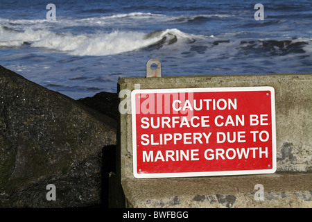 Rough sea and danger warning sign on jetty at Staithes in North Yorkshire. Stock Photo