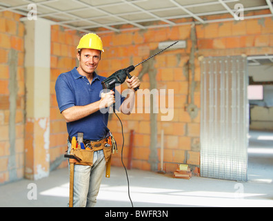 confident handyman with big drill on duty at construction site Stock Photo
