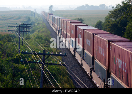 An intermodal freight train full of ocean containers rolls across the Illinois prairie on a summer afternoon. Stock Photo